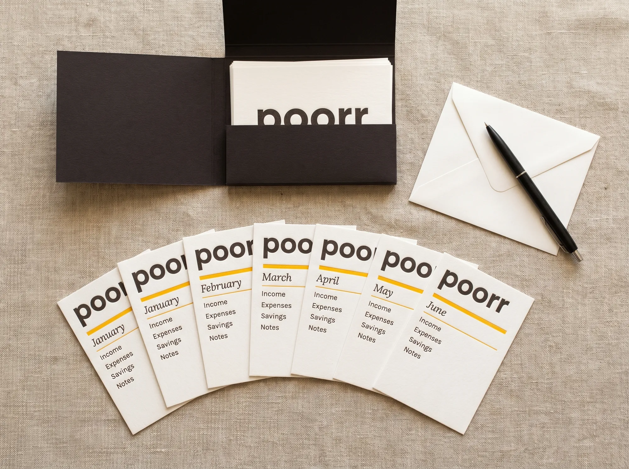 Poorr Money Card Set (Stationery) — A flat case of fifty letterpress monthly-budget cards used by readers — wordmark, month label, four envelope categories, single citrus-yellow rule.